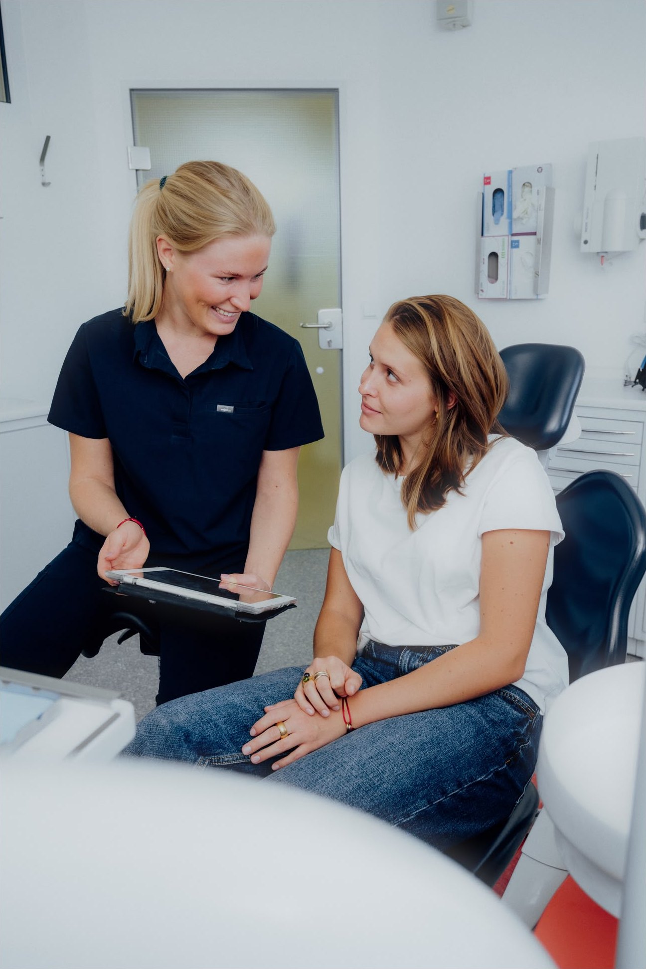Zahnärztin Dr. Charlotte Zimmermann bespricht mit einer Patientin die Behandlung auf dem Tablet